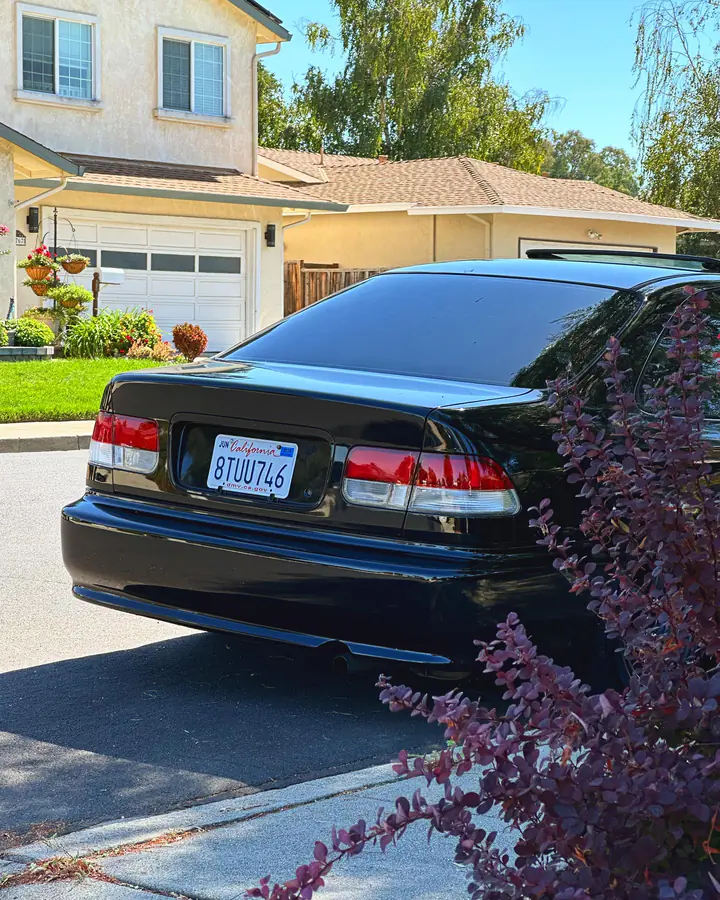 Rear three-quarter view of a black Honda Civic coupe in a Bay Area driveway